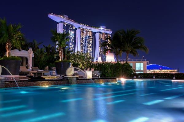 Illuminated Marina Bay Sands hotel above pool at night, capturing Singapore's iconic skyline.