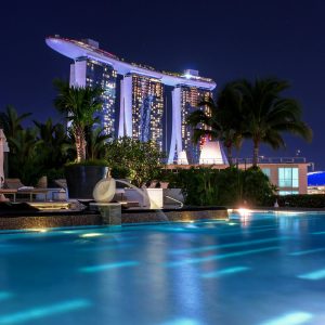 Illuminated Marina Bay Sands hotel above pool at night, capturing Singapore's iconic skyline.