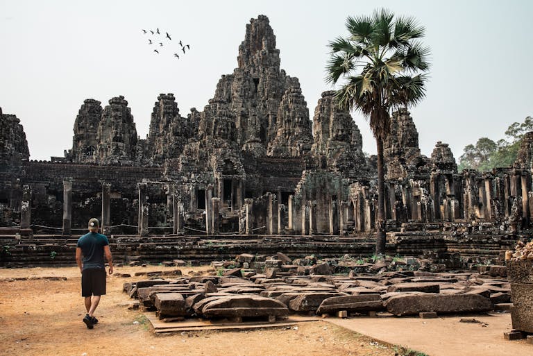 Photo by Tiago Cardoso Traveler exploring the ancient Bayon Temple at Angkor Thom, Cambodia, surrounded by stunning architecture.